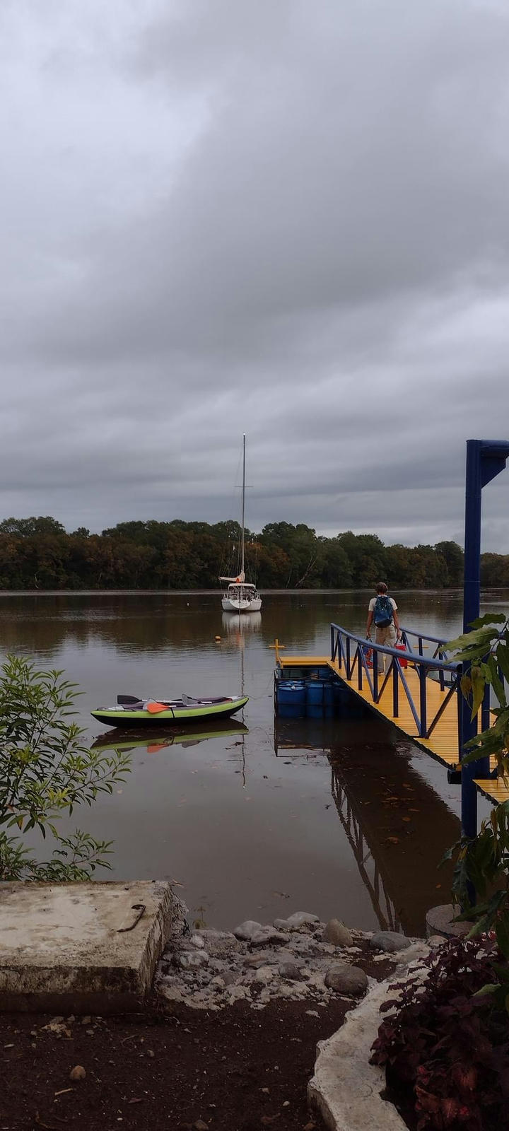 Yalcin walking on the dock with grocery to Tirb and kayak, vetical